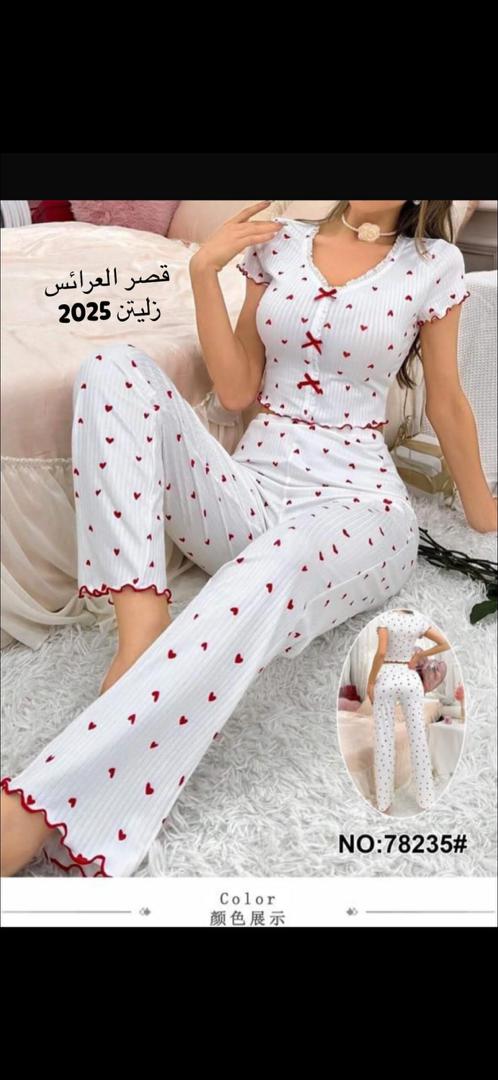 امرأة ترتدي طقماً أنيقاً مكوناً من بلوزة وسروال، تقف في متجر ملابس مع خلفية تعرض مجموعة متنوعة من الأزياء. النص الموجود في الصورة يقرأ قصر العرائس زليتن 2025، مما يضفي طابعاً عصريًا وثقة على المشهد.