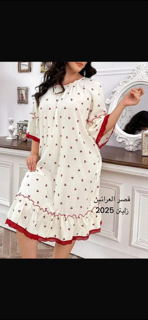 امرأة ترتدي طقماً أنيقاً مكوناً من بلوزة وسروال، تقف في متجر ملابس مع خلفية تعرض مجموعة متنوعة من الأزياء. النص الموجود في الصورة يقرأ قصر العرائس زليتن 2026، مما يضفي طابعاً عصريًا وثقة على المشهد.